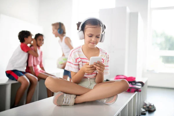Dziewczyna noszenie słuchawek słuchania muzyki i za pomocą smartfona — Zdjęcie stockowe