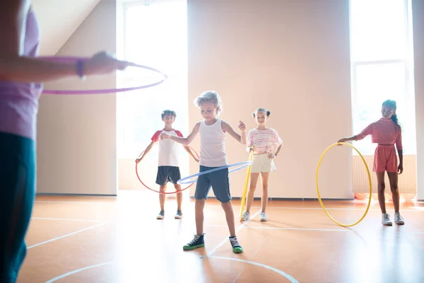 Jungen und Mädchen rollen beim körperlichen Training Hula-Hoop-Reifen — Stockfoto