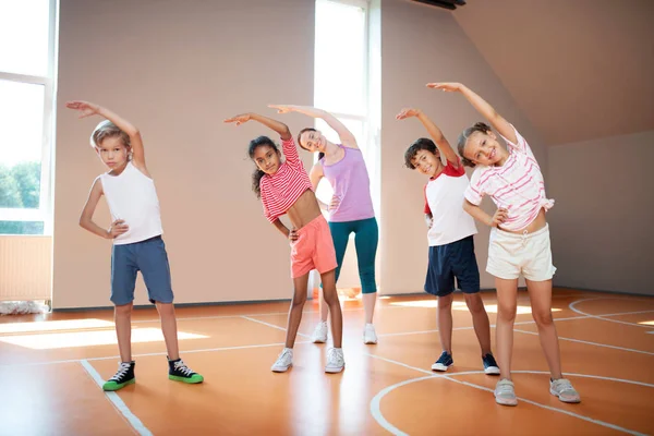 Alumnos y profesores de Educación Física trabajando en flexibilidad antes de comenzar la lección de Educación Física — Foto de Stock