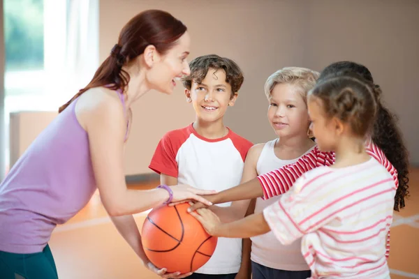PE nauczyciel i dzieci uśmiechnięty przed rozpoczęciem gry w koszykówkę — Zdjęcie stockowe