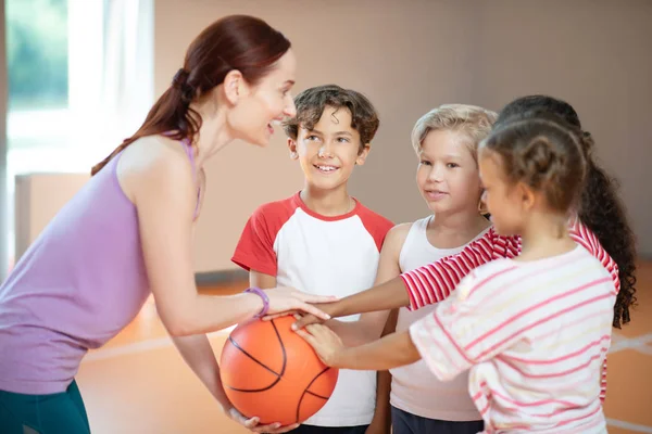 PE maestro y niños sonriendo antes de comenzar el juego de baloncesto — Foto de Stock