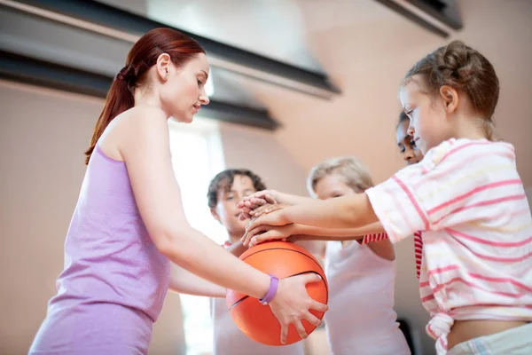 Учитель физкультуры держит баскетбольный мяч рядом с детьми — стоковое фото