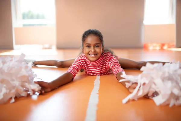 Little beaming cheerleader feeling happy while splitting legs — Stok Foto