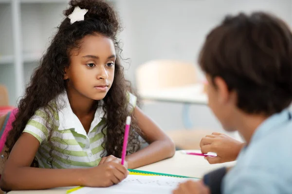 Милая темноглазая девушка слушает одноклассницу во время обсуждения теста — стоковое фото