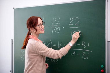 Gülümseyen matematik öğretmeni öğrencilerine yeni bir konu anlatıyor