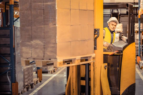 Soort grijs harige man die aan het magazijn werkt — Stockfoto