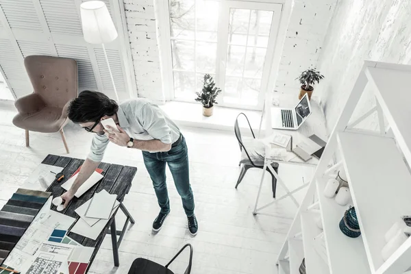 Vrolijke jonge kantoormedewerker die naar zijn tafel kijkt — Stockfoto