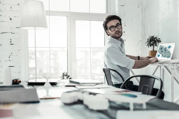 Blij bebaarde mannelijke persoon zittend op zijn werkplek — Stockfoto