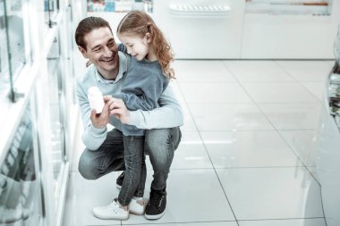 Çocuğa bakarken vitamin tutan gülen koyu saçlı baba