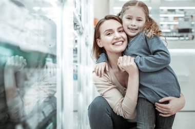 Anne gülerek ve eczacı dükkanında çocuk ile sarılma.