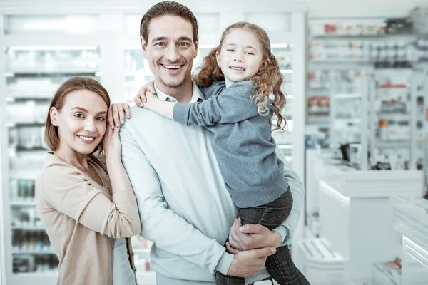 A cheerful family laughing and hugging near drugstore checkout