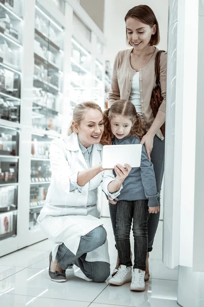 Criança olhando surpreendentemente para o tablet sugerido por um farmacêutico — Fotografia de Stock