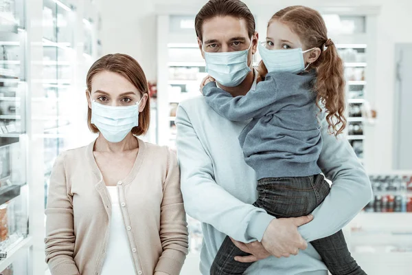 Family in the drugstore wearing a medical face mask — Stock Photo, Image