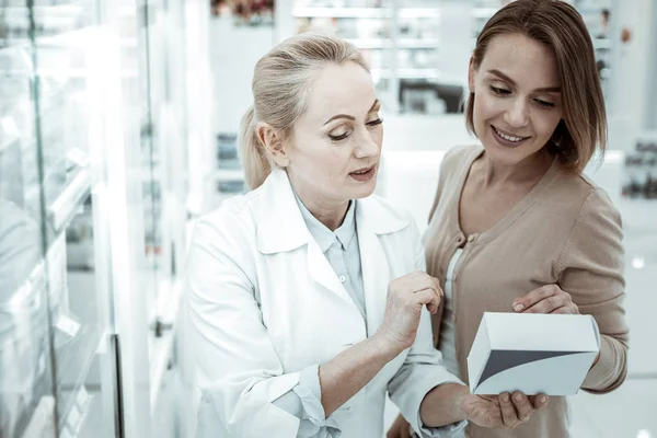 Hyvä houkutteleva apteekkarin johtaja, joka neuvottelee ostajan kanssa lääkkeen valinnasta — kuvapankkivalokuva