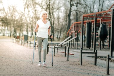 İskandinav yürüyüşü. Spor sahasında İskandinav yürüyüş yapıyor iyi sportif bir şekil yaşlı gülme hoş kadın.