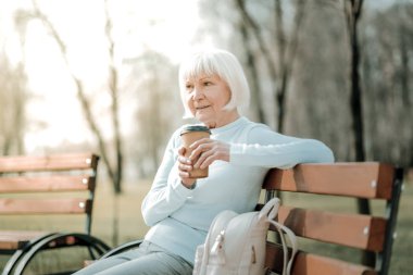 Septuagenarian granny park koltuğunda kahve zevk alarak.