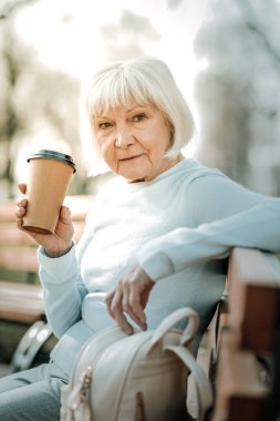 Mavi durulanmış zarif bayan kahve bir kağıt fincan tutan.