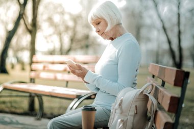Sunuma uygun kadın bir fincan kahve ile telefonunu kontrol