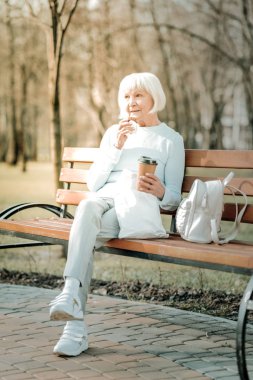 Yaşlı missis park alanında kahve ve çerez zevk