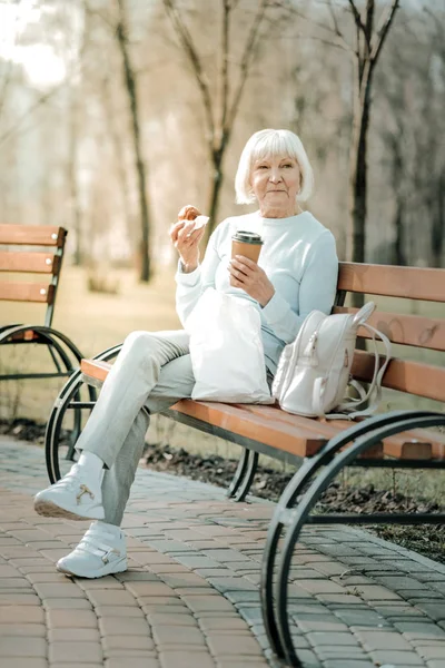 Veselá a krásná stará dáma ochutnáváním kávy a koláče — Stock fotografie