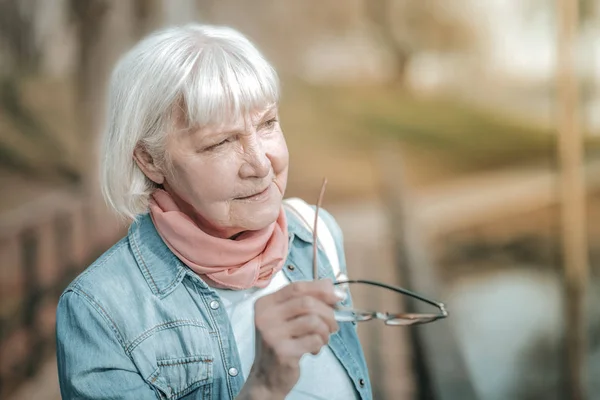 Elegante graziosa signora invecchiamento tenendo i suoi occhiali in una mano — Foto Stock