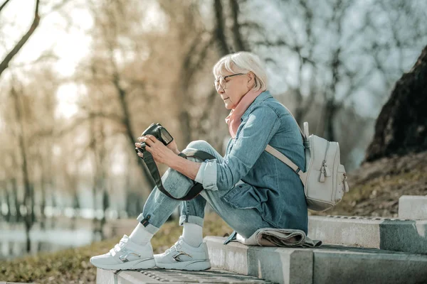 Senior madam de moda sentado en los escalones del parque con la cámara — Foto de Stock