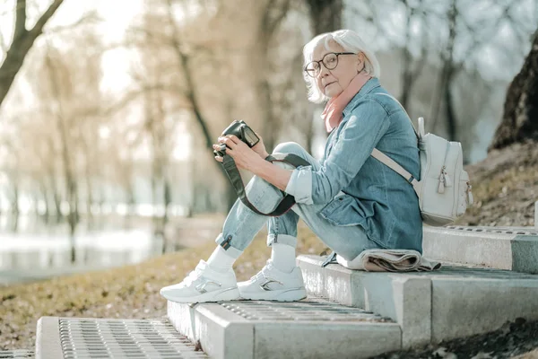 Стареющая улыбающаяся очаровательная женщина, занимающаяся фотографией в парке — стоковое фото