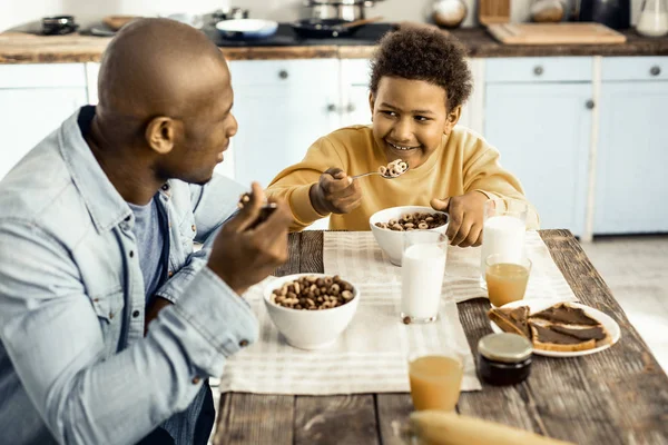 건강한 음식을 먹고 휴일에 대해 이야기하는 아들과 함께 즐거운 아프리카 계 미국인 아빠. — 스톡 사진
