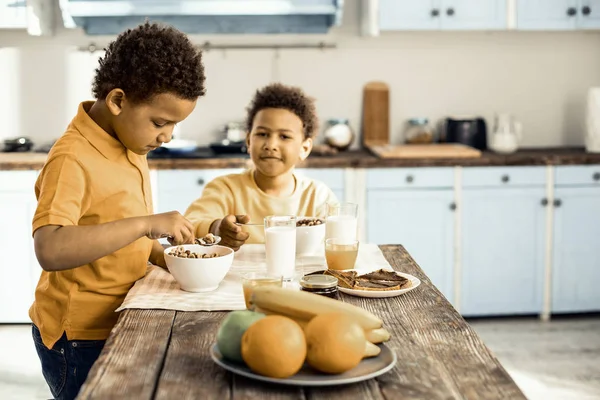 Süße afroamerikanische Zwillinge frühstücken vor der Schule. — Stockfoto