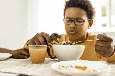 Plastik bir dinozor ve pul ile oynayan çocuk.