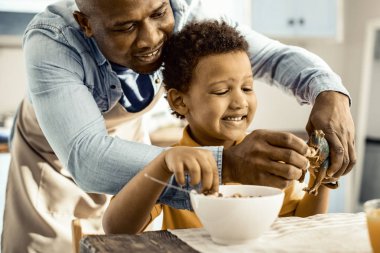 Oğluyla oyuncak besliyormuş gibi önlüklü baba.