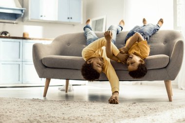 Çocuklar kanepede baş aşağı yalınayak yatarken ve gülüyorlar..