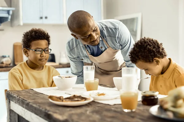 Papá alimentando a los gemelos con el desayuno y preguntándoles es sabroso . — Foto de Stock