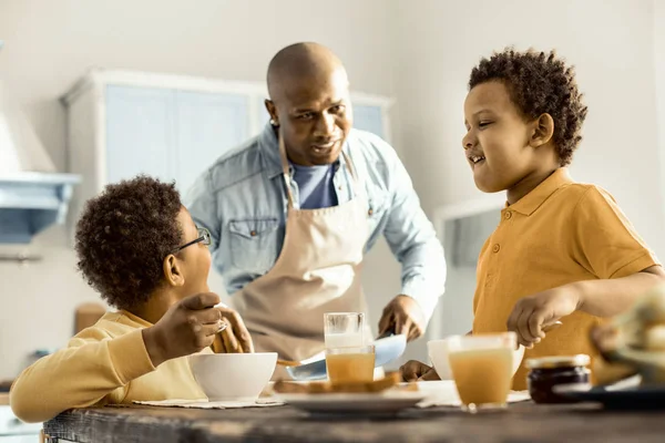 Man asking his sons not to swear in the kitchen while eating.