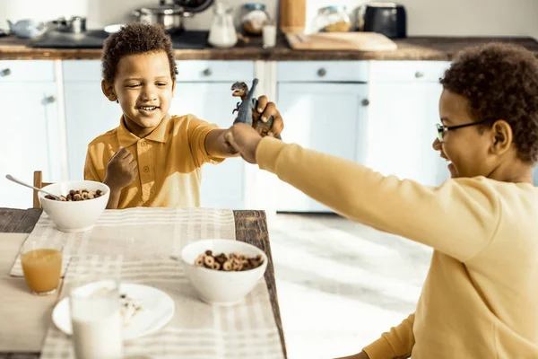 Brothers staging a battle of dinosaurs during lunch. — Stock Photo, Image