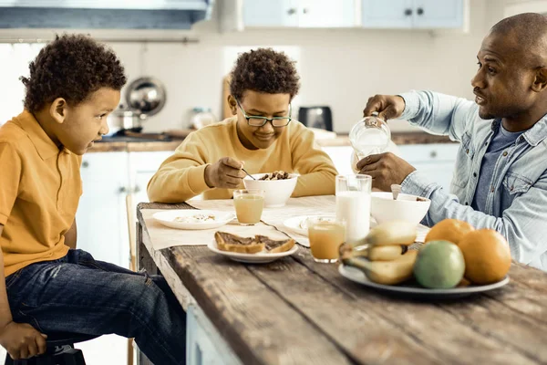 Vader bereidt ontbijt voor zijn zonen en eindelijk zitten om te eten met hen. — Stockfoto