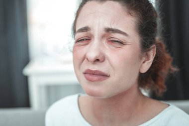 Mature woman with facial wrinkles crying having allergy clipart