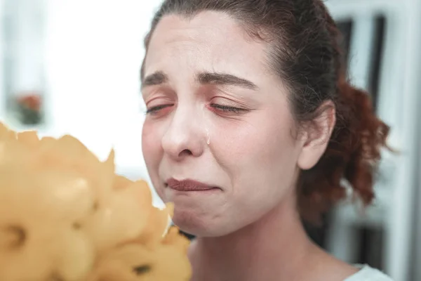 Curly housewife having tears because of allergy to flowers — Stock Photo, Image
