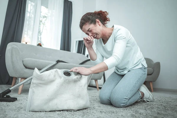 Ama de casa sentada en el suelo y estornudos con alergia al polvo — Foto de Stock