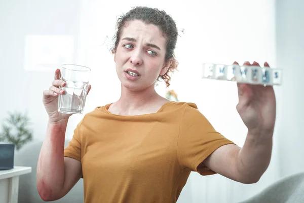 Mujer con enrojecimiento en píldoras para beber del brazo para tratar la alergia — Foto de Stock