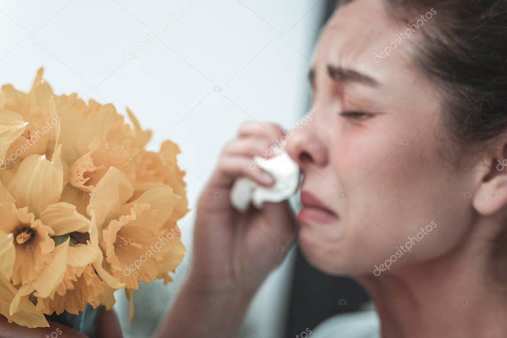 Mature woman sneezing while having allergy to flowers