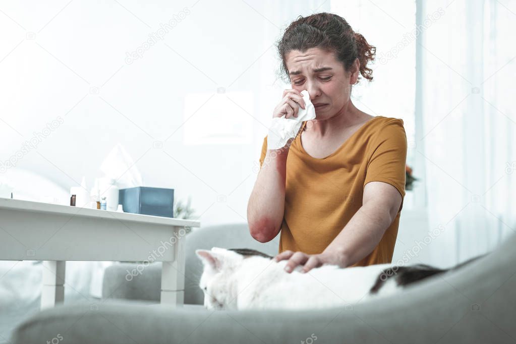 Wife sitting on sofa having strong allergy to cats and dust