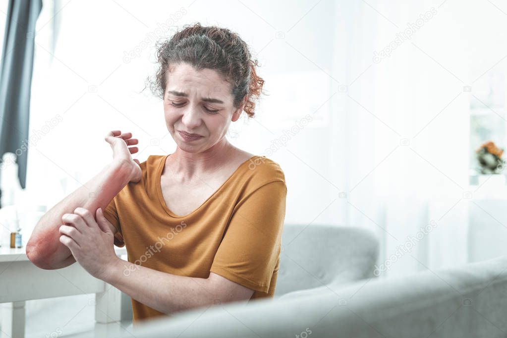 Curly red-haired woman feeling ache on her arm after allergy