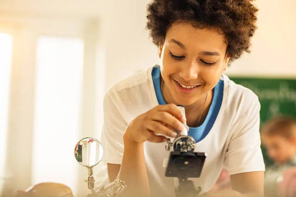 Radostný teenager s použitím mikroskopu při přípravě na lekci — Stock fotografie