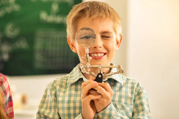 Ragazzo felice positivo che gioca con lente d'ingrandimento — Foto Stock