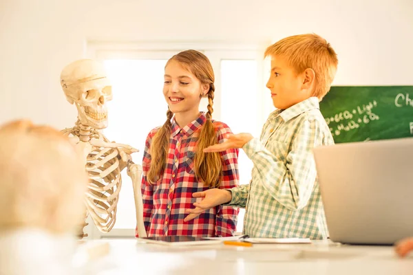 Zadowolony Blondynka dzieci patrząc na sztuczny szkielet — Zdjęcie stockowe