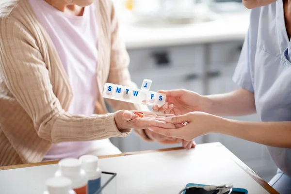 护理人员把药片放在退休妇女的手掌上 — 图库照片