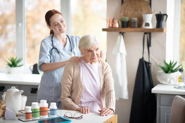 Caregiver doing some shoulder massage for aged woman — Stock Photo, Image