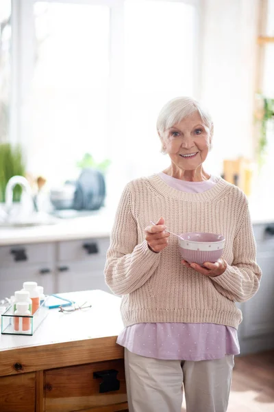 Usmívající se žena s penzionovou nádobkou při snídani — Stock fotografie