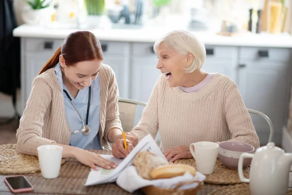 Pflegerin und ihr Patient lachen beim Lesen von Nachrichten — Stockfoto